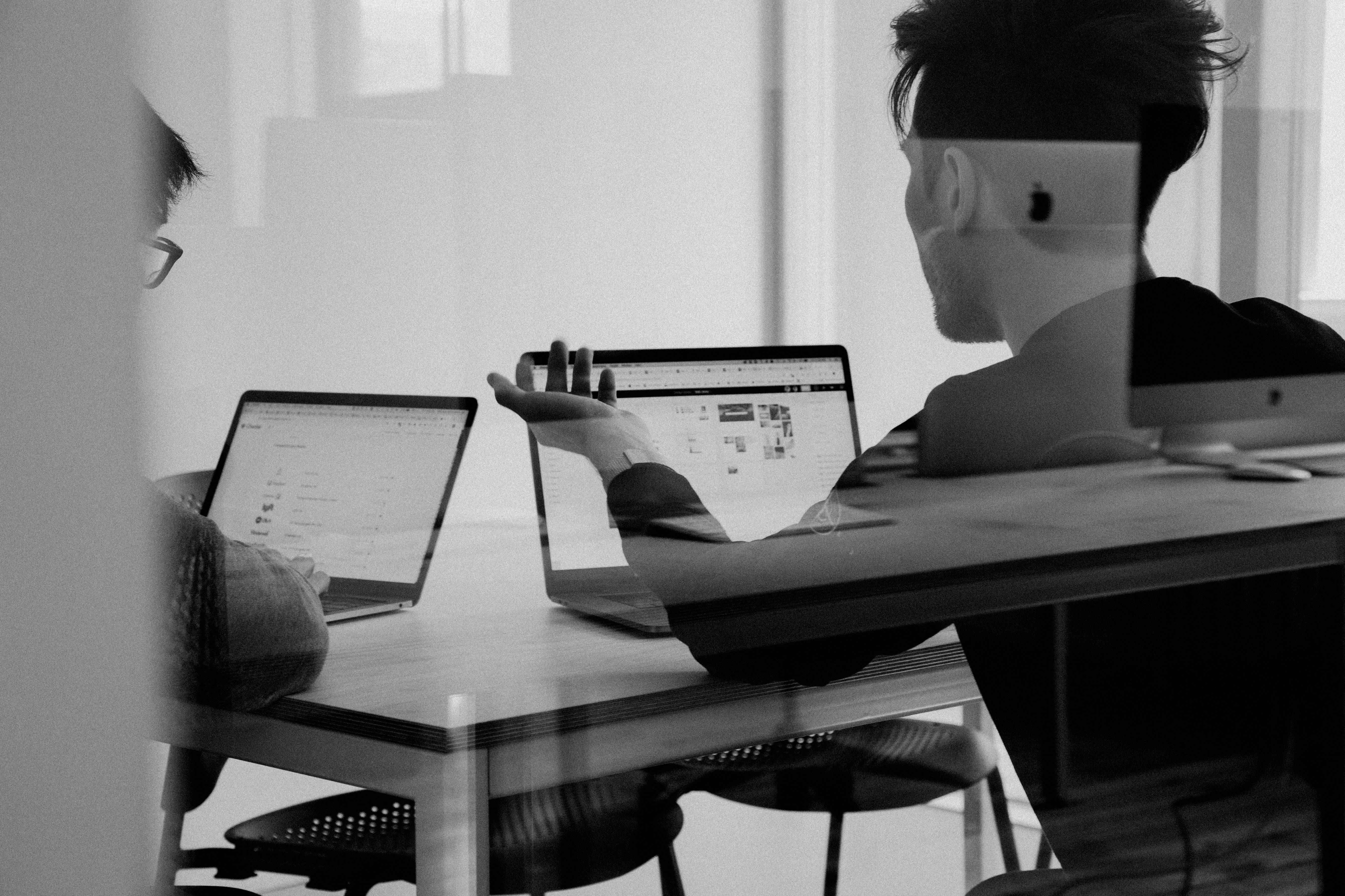 Photo of two people sitting at a table with a laptop